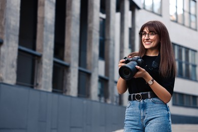 Professional photographer with digital camera near building outdoors. Space for text