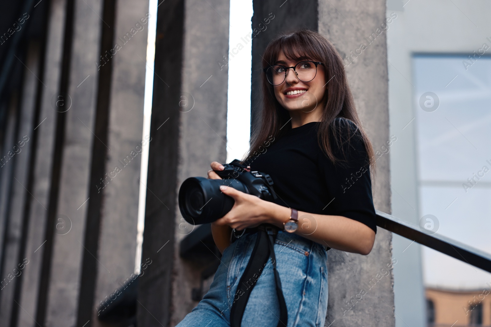 Photo of Professional photographer with digital camera outdoors, low angle view