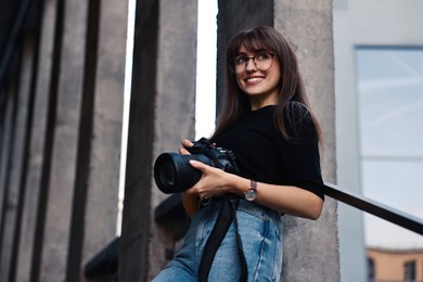 Photo of Professional photographer with digital camera outdoors, low angle view