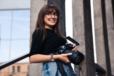 Photo of Professional photographer with digital camera outdoors, low angle view