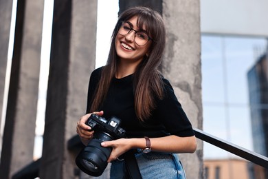 Professional photographer with digital camera near building outdoors