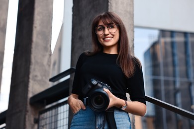 Professional photographer with digital camera near building outdoors