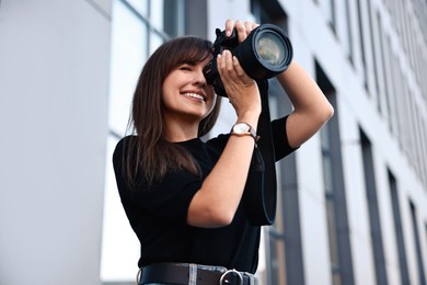 Photo of Professional photographer taking picture with camera outdoors, low angle view