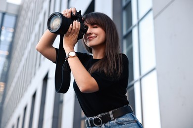 Photo of Professional photographer taking picture with camera outdoors, low angle view