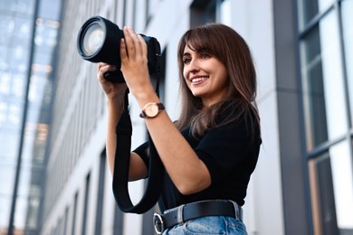 Professional photographer with digital camera near building outdoors