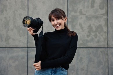 Photo of Professional photographer with digital camera near grey wall outdoors