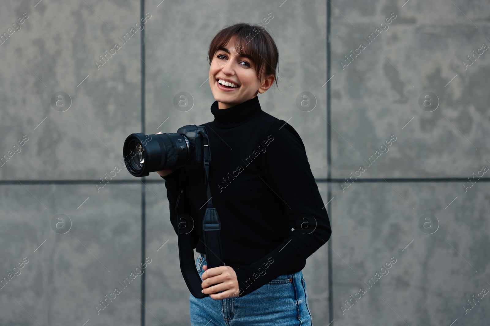 Photo of Professional photographer with digital camera near grey wall outdoors