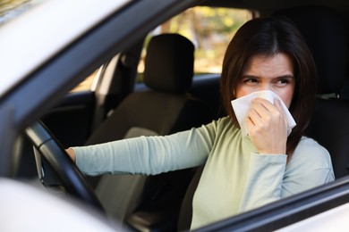 Young woman with runny nose in car