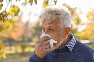 Photo of Senior man with runny nose in park, space for text