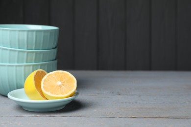 Stack of empty bowls and lemon on grey wooden table. Space for text