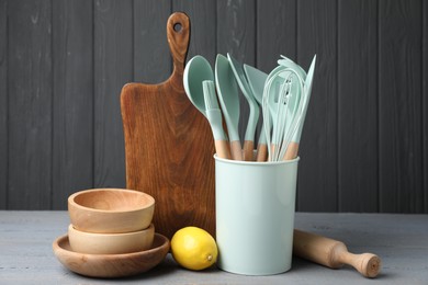 Photo of Dishware, cooking utensils and lemon on grey wooden table