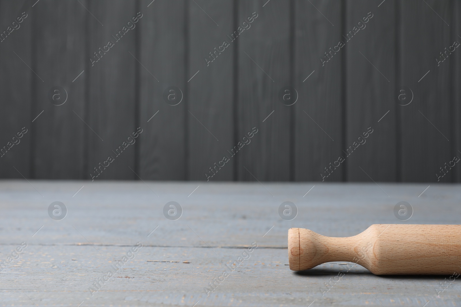 Photo of Rolling pin on grey wooden table, space for text. Cooking utensil