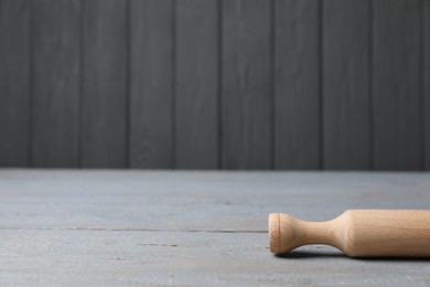 Rolling pin on grey wooden table, space for text. Cooking utensil