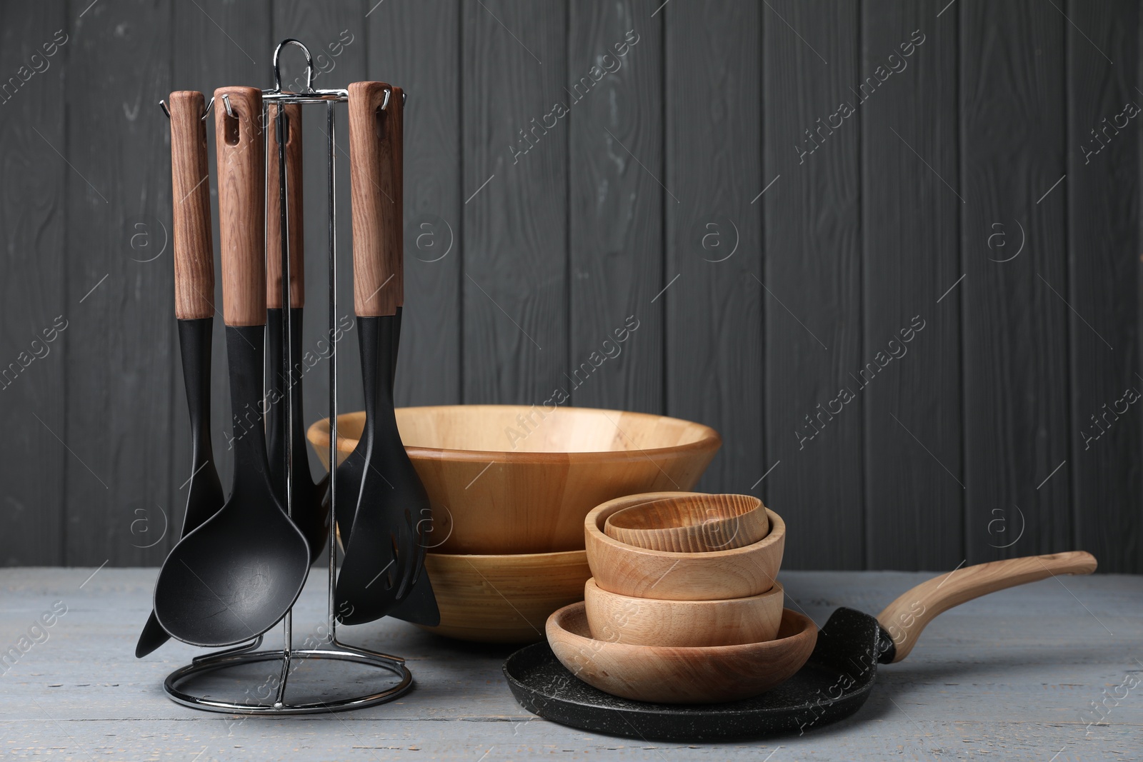 Photo of Dishware and cooking utensils on grey wooden table. Space for text