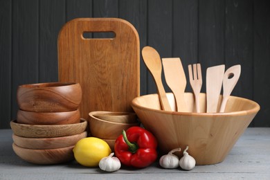 Photo of Dishware, cooking utensils, lemon, garlic and pepper on grey wooden table