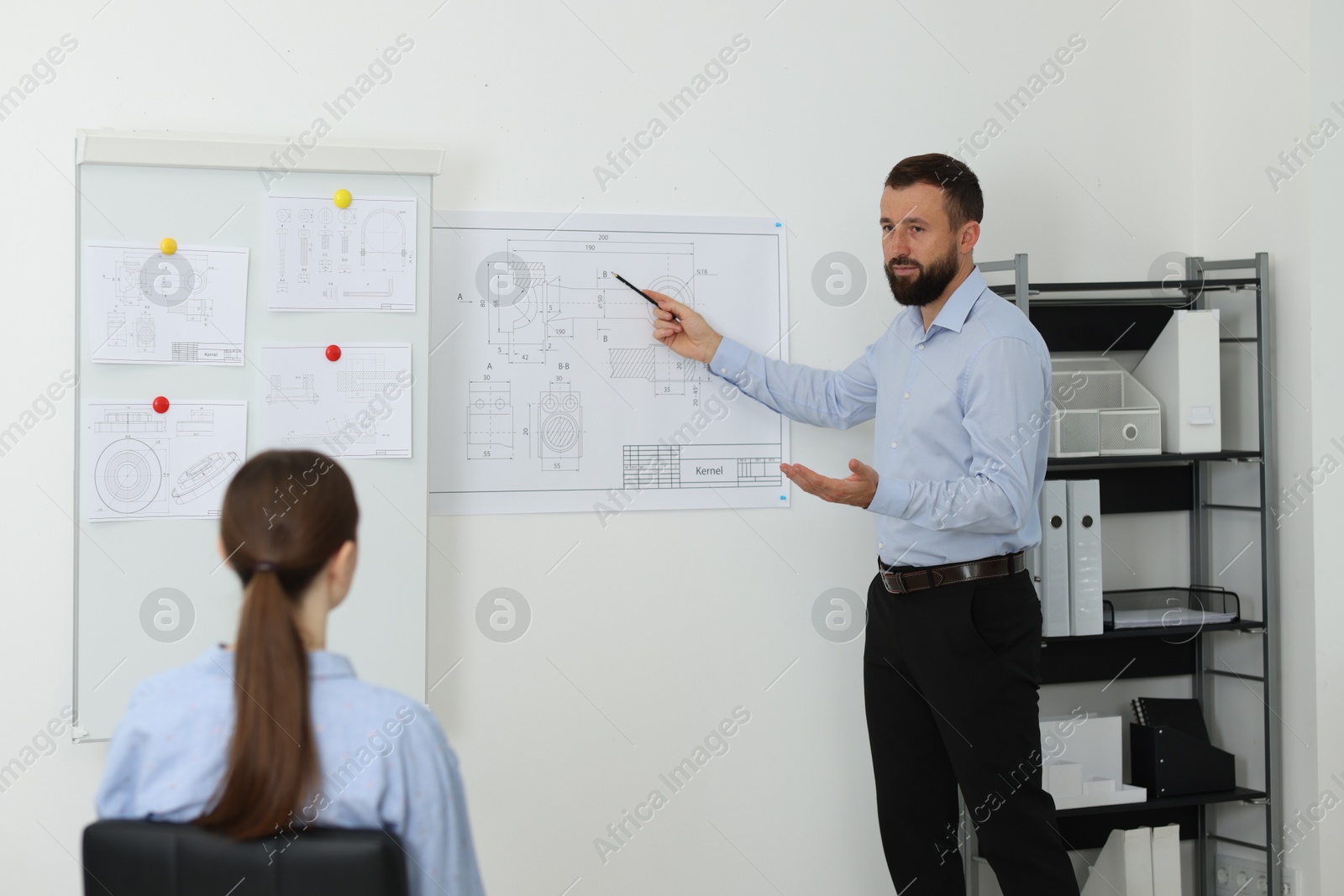 Photo of Man making presentation with engineering drawings to his colleagues in office