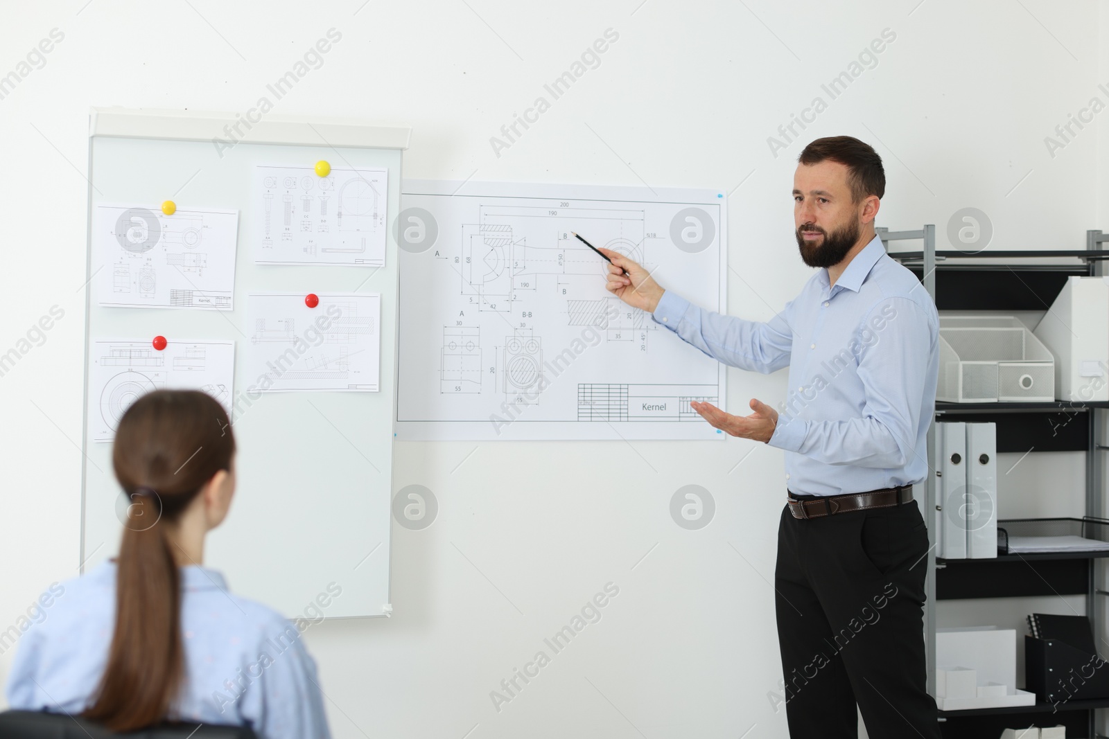 Photo of Man making presentation with engineering drawings to his colleagues in office