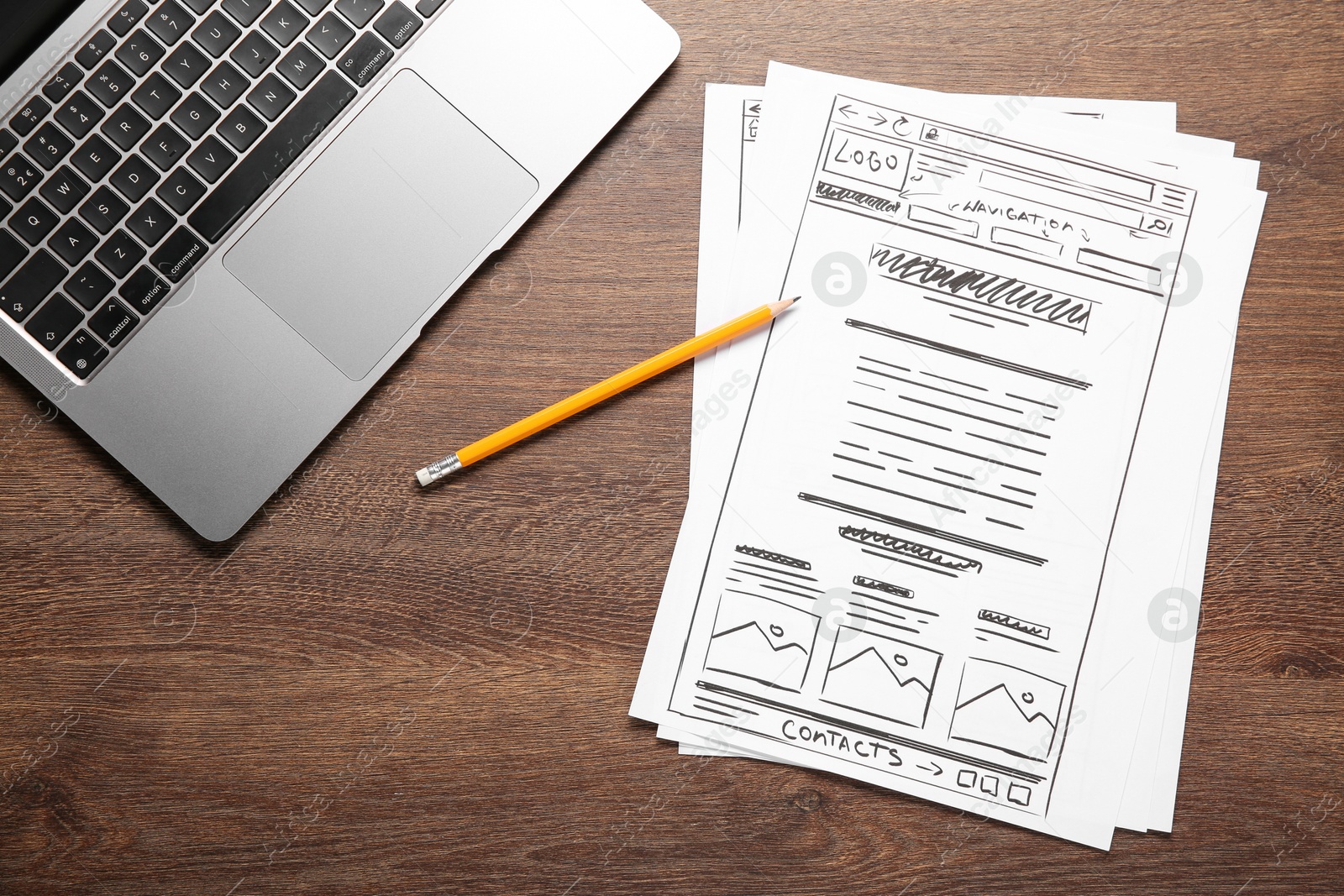 Photo of Developing UI design. Sketches of website wireframes, pencil and laptop on wooden table, top view