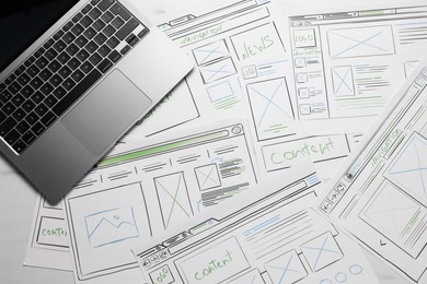 Photo of Developing UI design. Sketches of website wireframes and laptop on table, top view