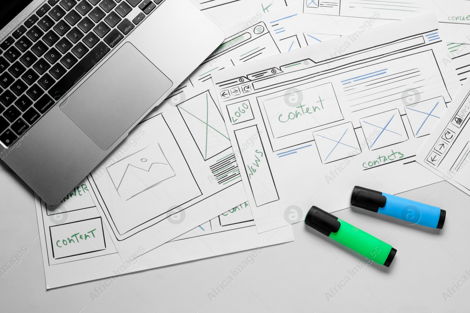 Photo of Developing UI design. Sketches of website wireframes, laptop and felt pens on white marble table, top view