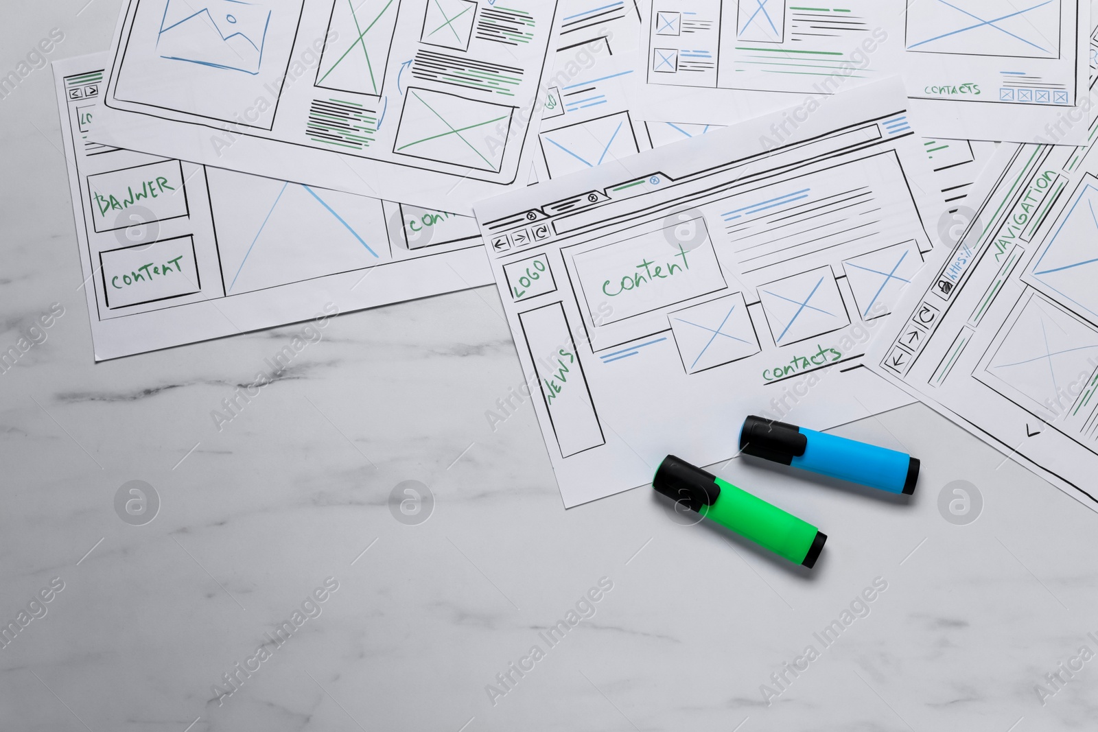 Photo of Developing UI design. Sketches of website wireframes and felt pens on white marble table, top view