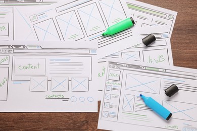 Photo of Developing UI design. Sketches of website wireframes and felt pens on wooden table, top view