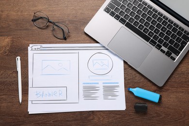 Photo of Developing UI design. Sketches of website wireframes, laptop, glasses and stationery on wooden table, top view