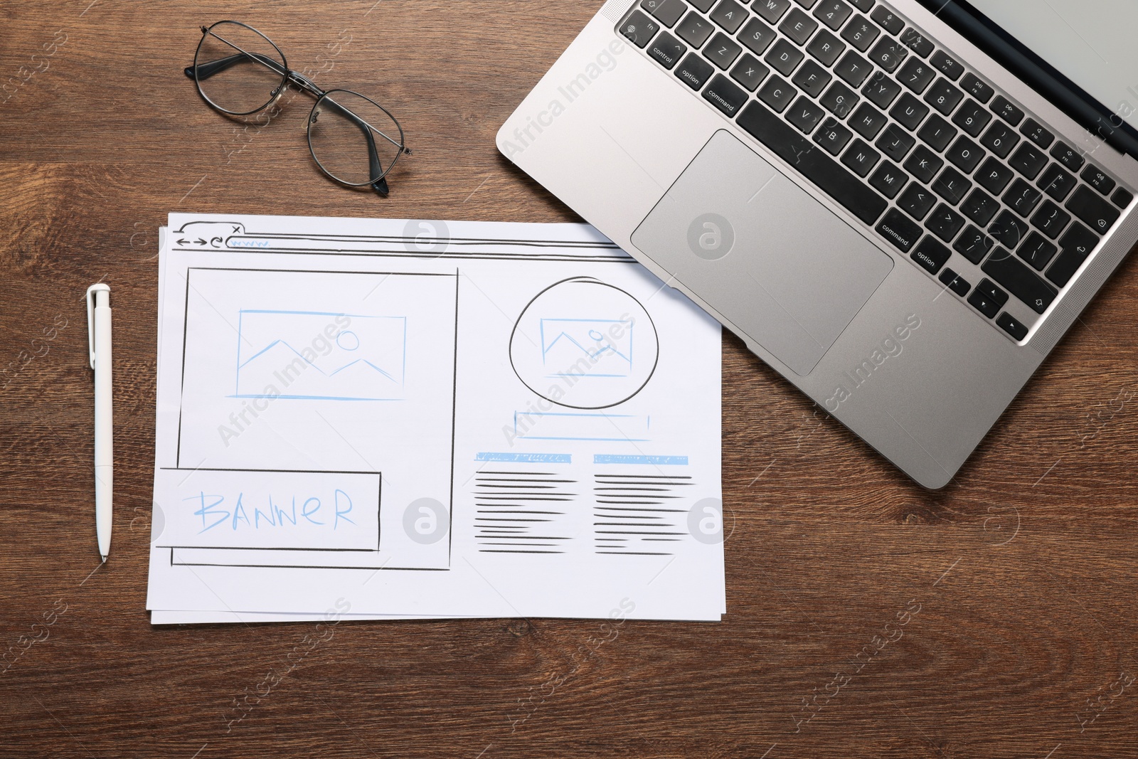 Photo of Developing UI design. Sketches of website wireframes, laptop, glasses and pen on wooden table, top view