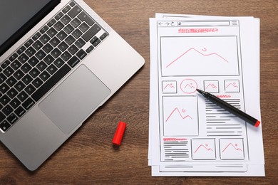 Photo of Developing UI design. Sketches of website wireframes, laptop and felt pen on wooden table, top view