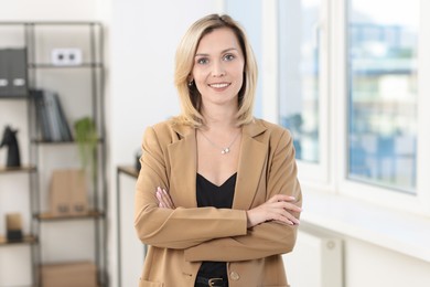 Portrait of happy businesswoman with crossed arms in office