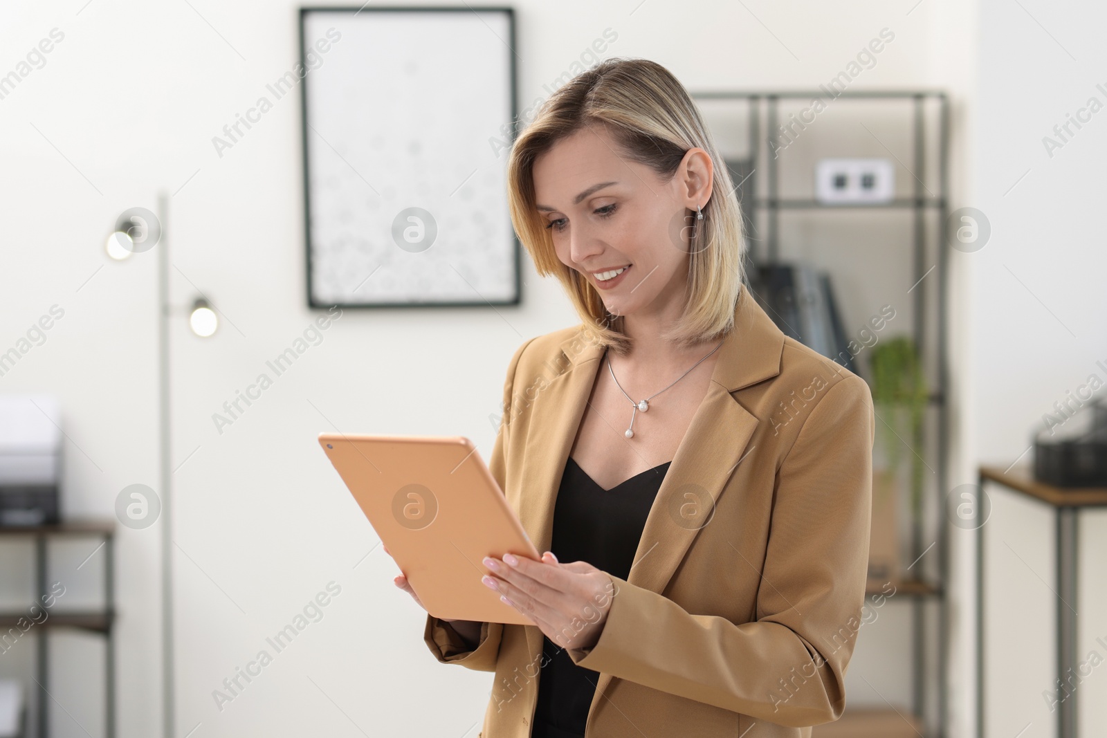 Photo of Portrait of happy businesswoman using tablet in office