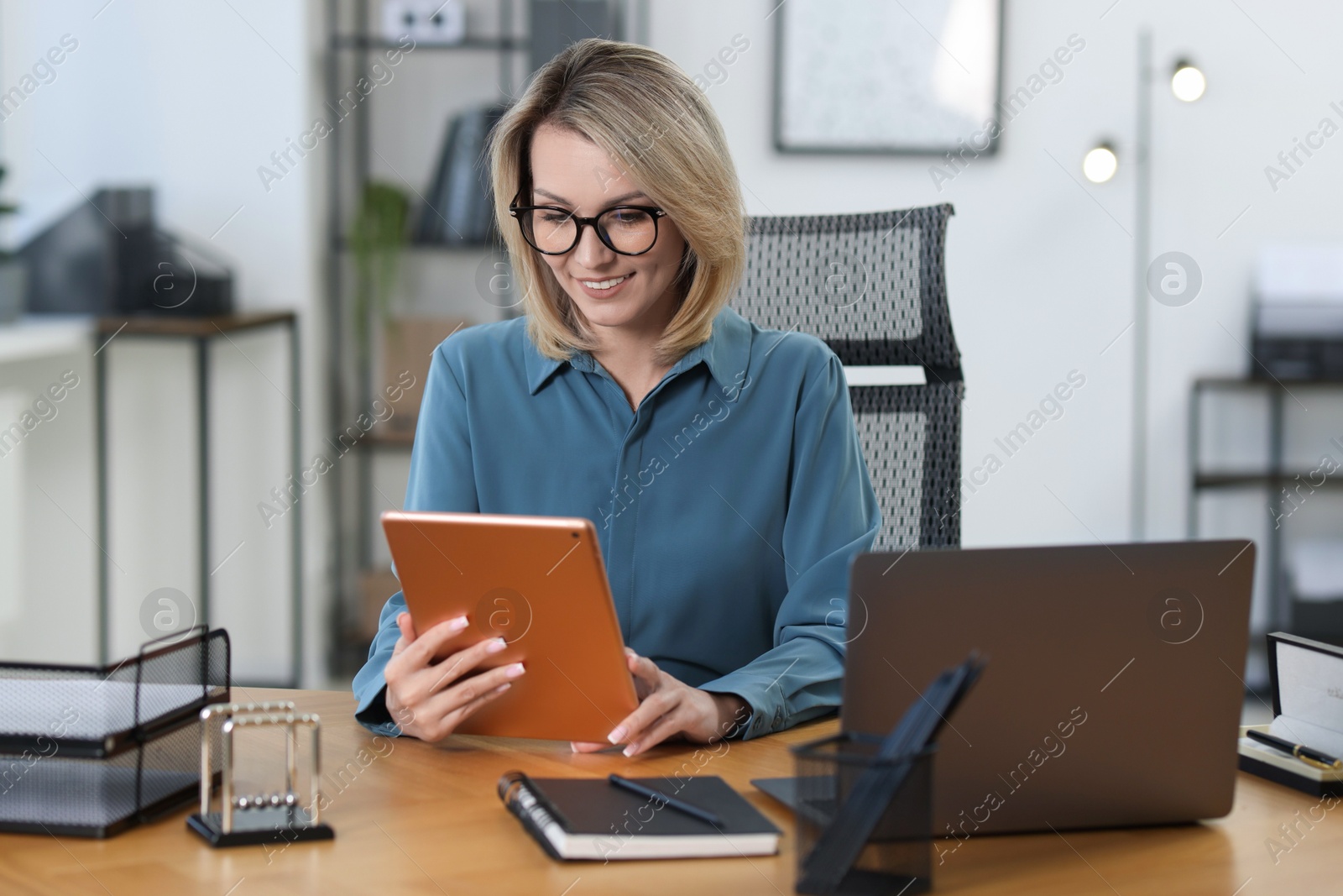 Photo of Businesswoman using tablet at table in office