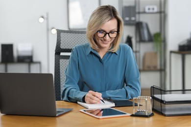 Photo of Businesswoman taking notes at table in office