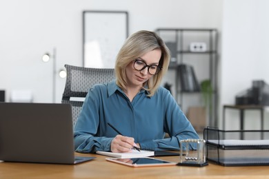 Businesswoman taking notes at table in office