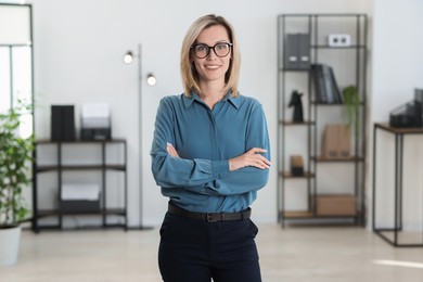 Photo of Portrait of happy businesswoman with crossed arms in office