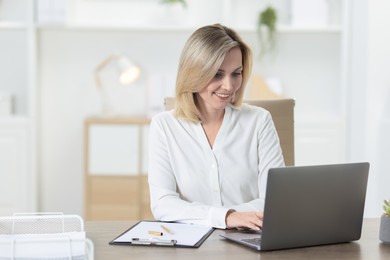 Photo of Businesswoman working on laptop at table in office