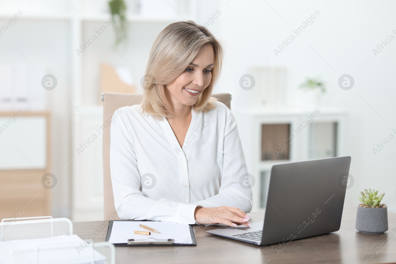 Photo of Businesswoman working on laptop at table in office