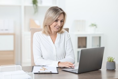 Photo of Businesswoman working on laptop at table in office