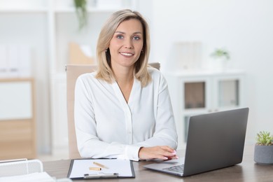 Photo of Businesswoman working on laptop at table in office