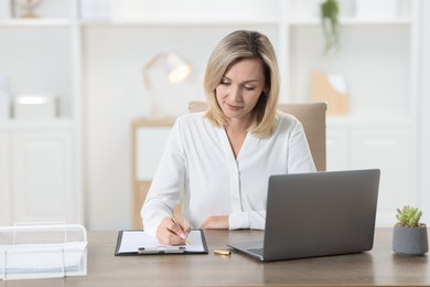 Photo of Businesswoman taking notes at table in office