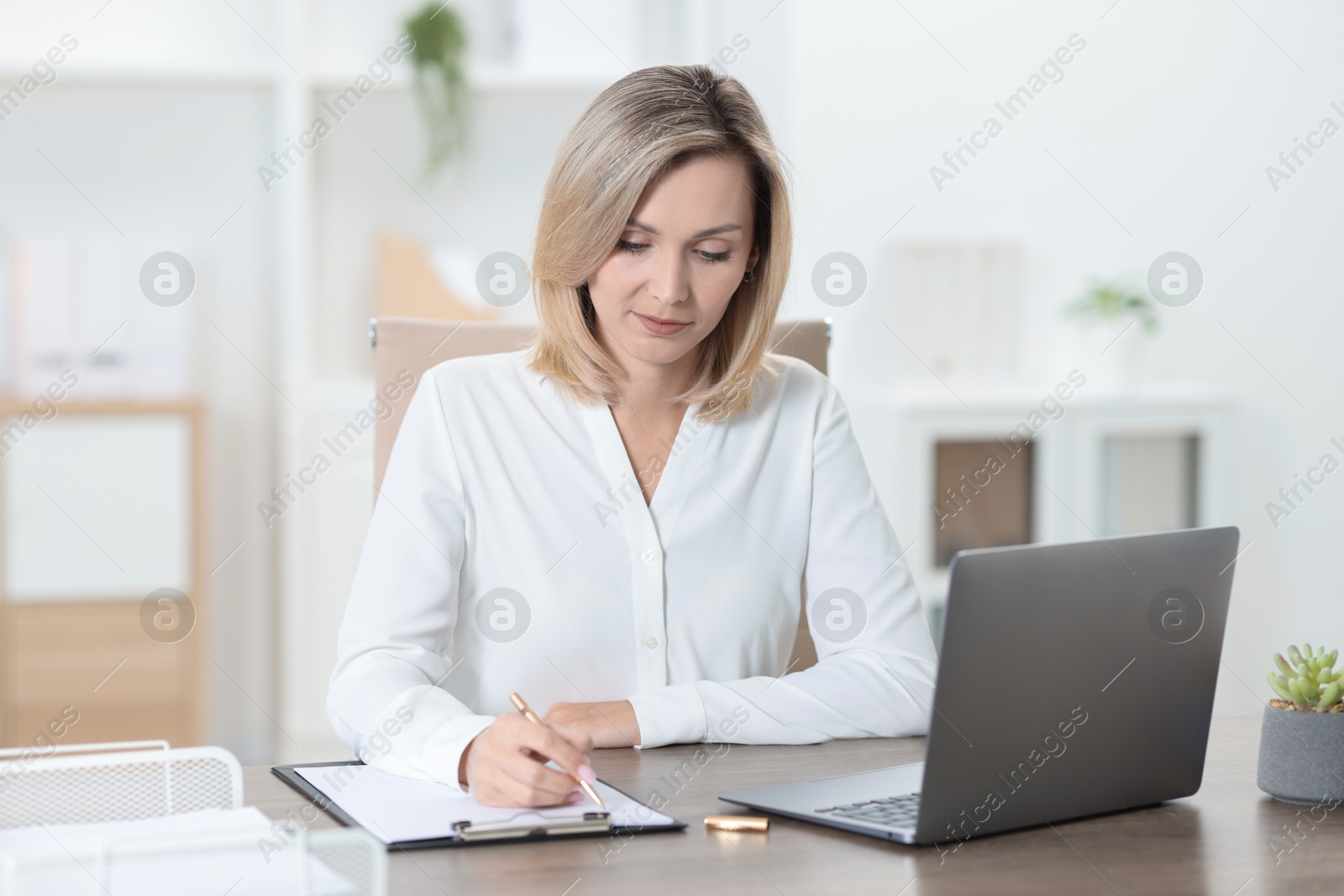 Photo of Businesswoman taking notes at table in office