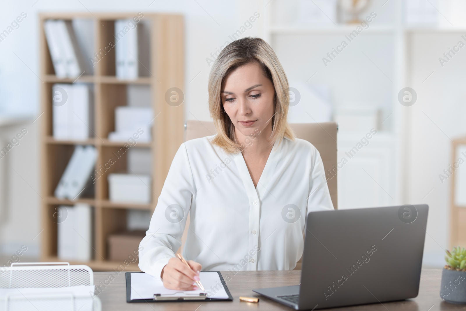 Photo of Businesswoman taking notes at table in office