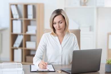 Businesswoman taking notes at table in office