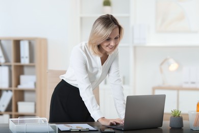 Photo of Businesswoman working on laptop at table in office