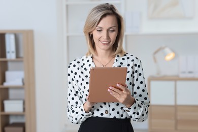 Photo of Portrait of happy businesswoman using tablet in office