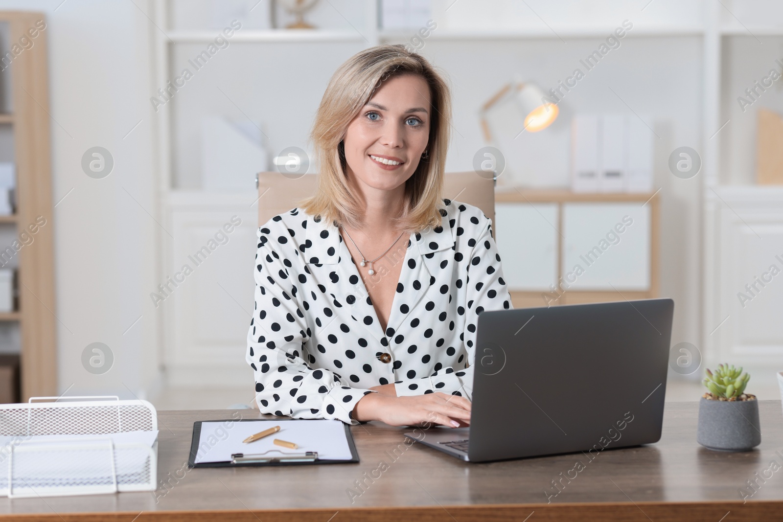 Photo of Businesswoman working on laptop at table in office