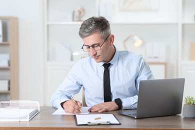 Photo of Businessman taking notes at table in office