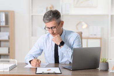 Businessman taking notes at table in office