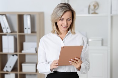 Photo of Portrait of happy businesswoman using tablet in office