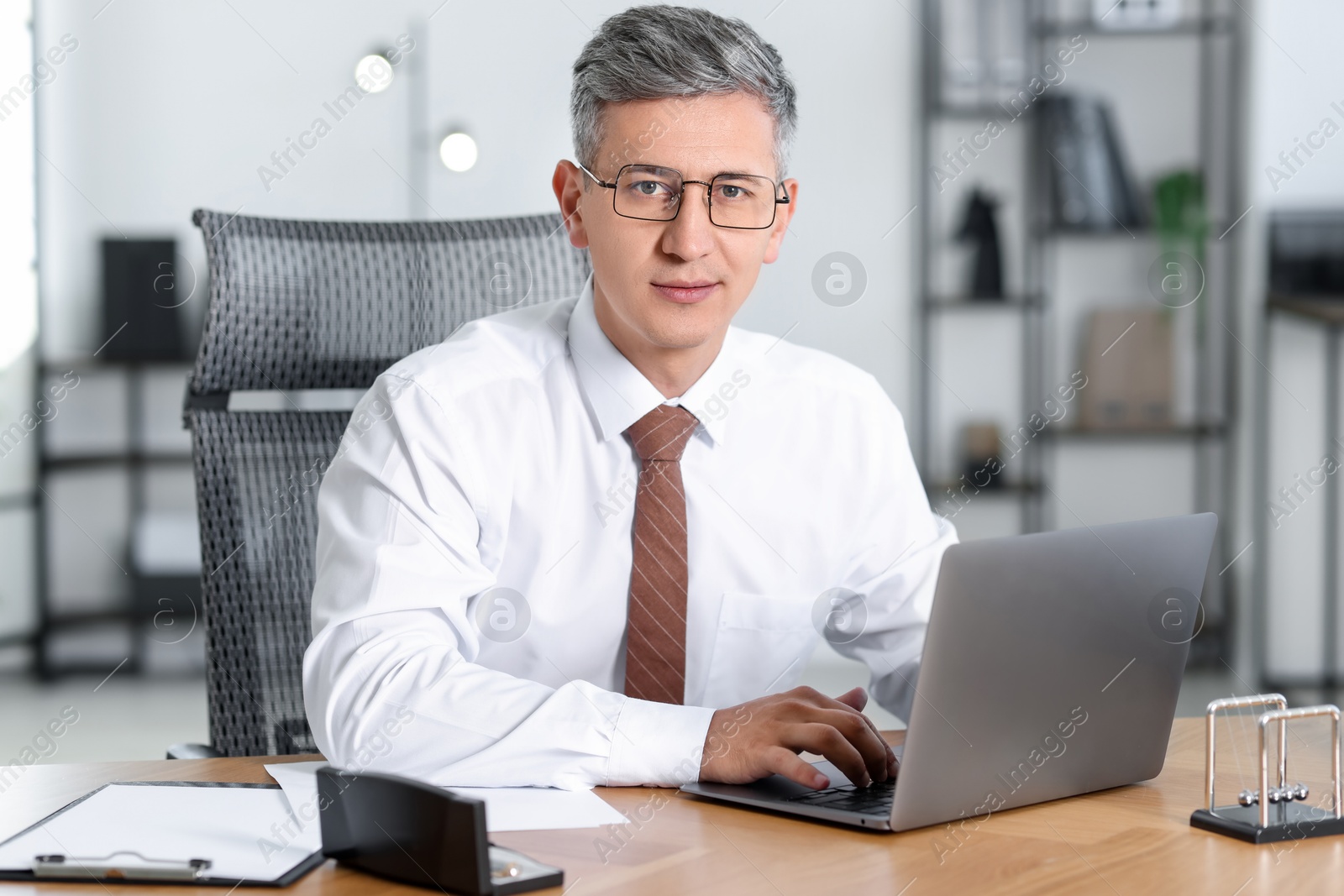 Photo of Businessman working on laptop at table in office